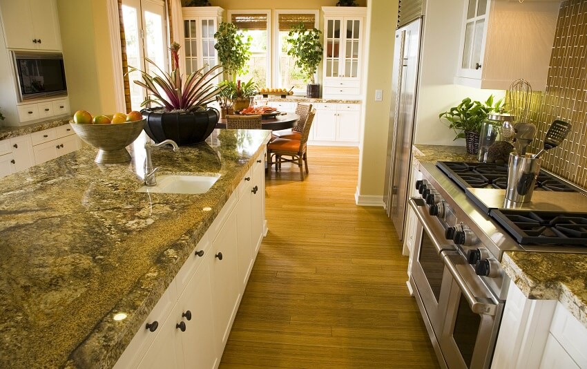 Kitchen with island serpentine countertops brick backsplash white cabinets stainless steel appliance and view of the dining area