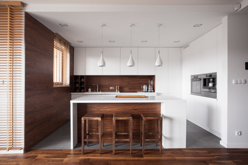 Kitchen with low ceiling, pendant lights, center island, white cabinets, and wood accent wall