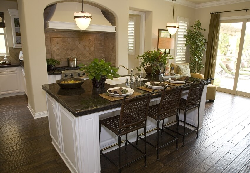 Kitchen with modern serpentine island rattan bar stools pendant light hardwood floors brick backsplash and glass doors
