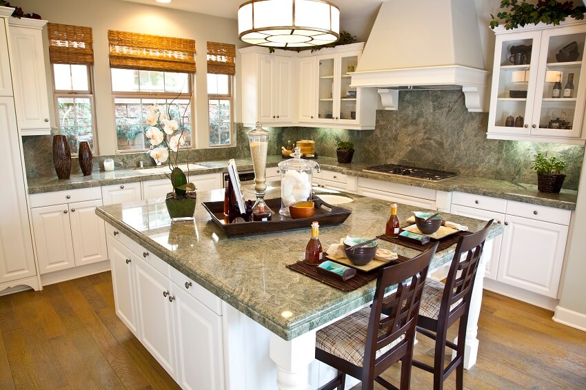 Kitchen with tray utensils and decors on island white cabinets window wood floors and serpentine countertops and backsplash