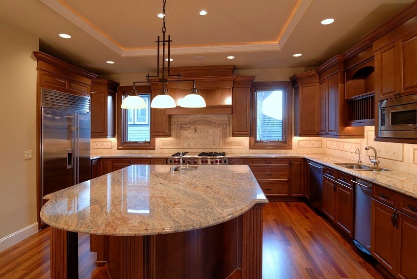 Large kitchen with dark wood floors island and cabinets natural stone countertops lighting fixtures and tile backsplash