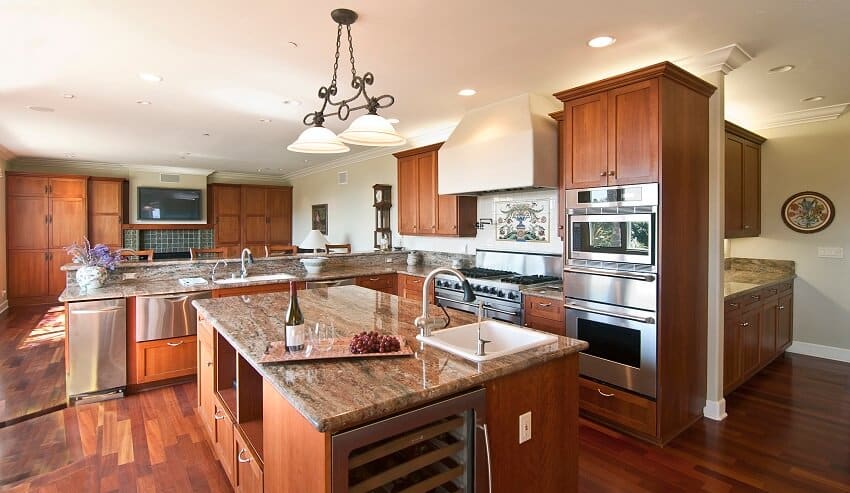 Large modern kitchen with wood floors and cabinets stainless steel appliances natural stone countertops and island with built in wine storage and sink