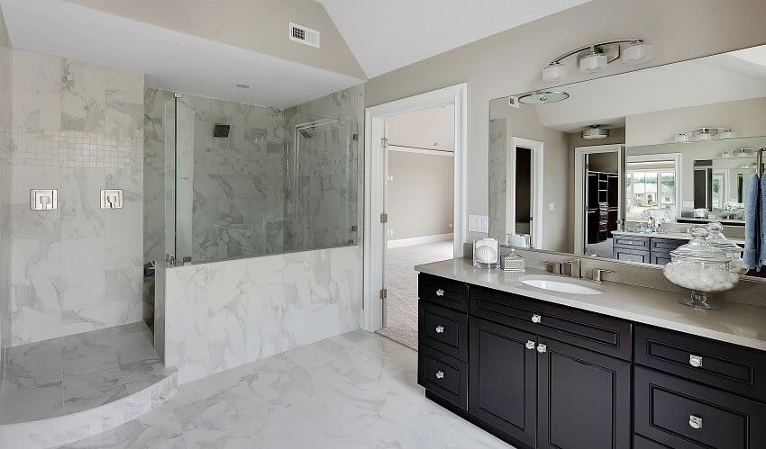 Large walk in shower with beautiful marble walls black cabinets large mirror and lighting fixtures
