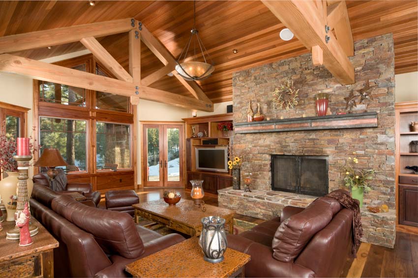 Living room sloped wood ceiling flush mount lights exposed beams leather sofa chairs brick fireplace