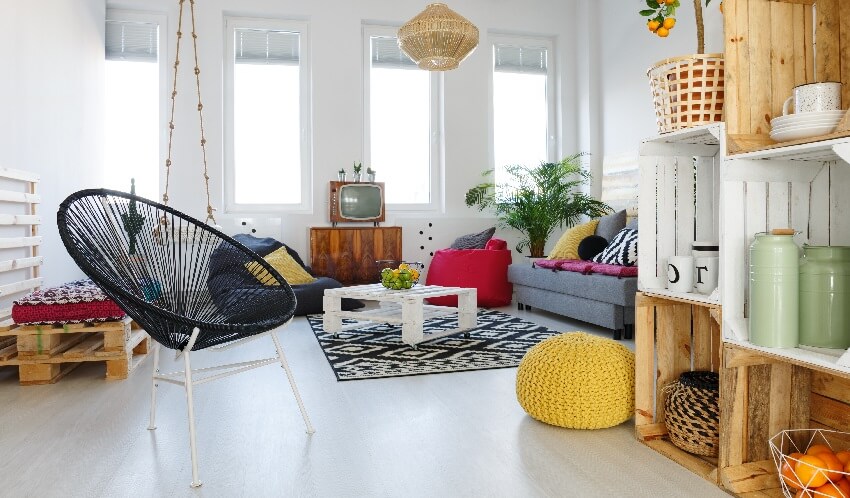 Room with black chair, yellow pouf sofa and pallet furniture