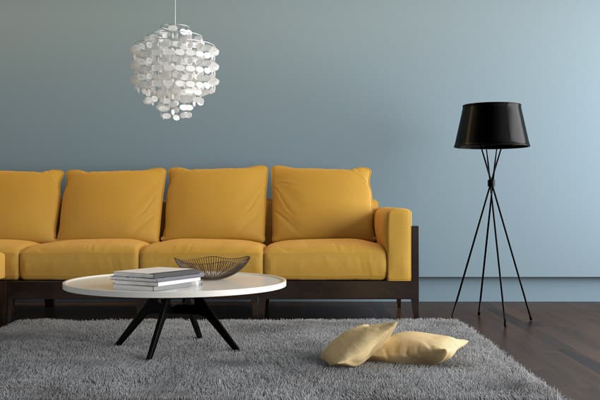 Minimalist floor lamp yellow couch wood floor pastel blue wall rug coffee table hanging light