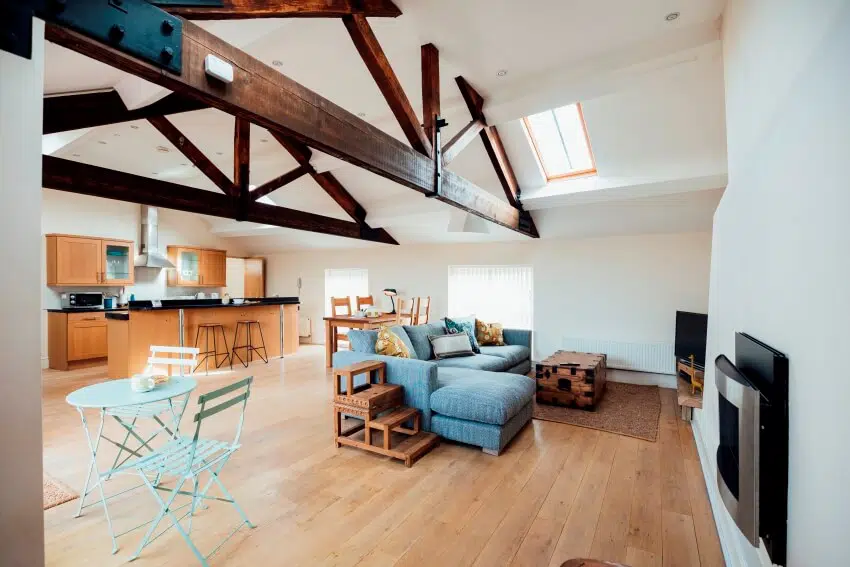 Home with slanted walls and exposed beams showing the living and kitchen area