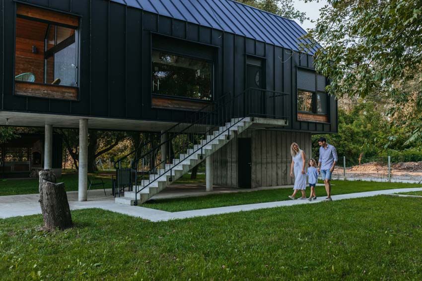 Modern home with black siding family walking pathway stairs glass windows