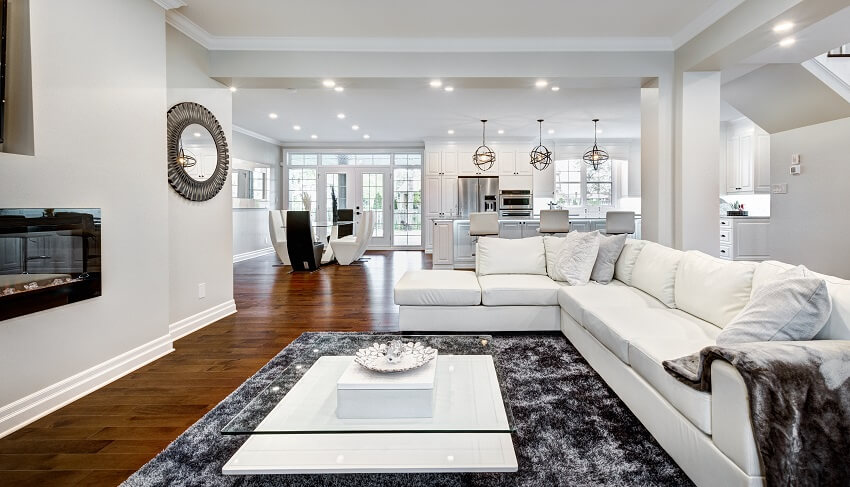 Modern house with dark wood floors fireplace white furnitures carpet and view of the kitchen and dining area