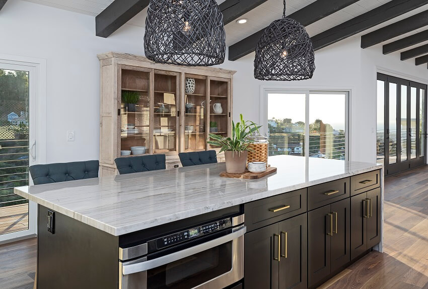 Modern kitchen with ceiling beams black rattan pendant lights glass door cabinet large glass doors and island with mother of pearl quartzite countertop