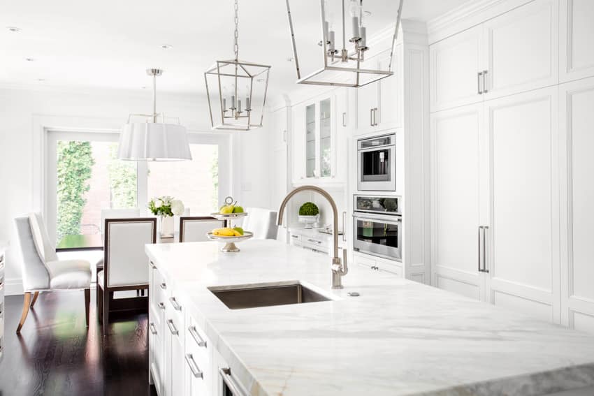 Modern kitchen with granite marble countertop sink white cabinets wood floor windows chairs hanging lights