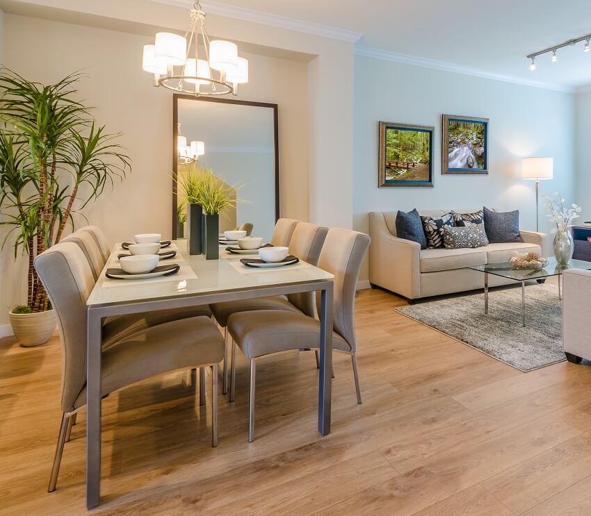 Modern living and dining area with table with beige chairs, lighting fixtures and indoor plant