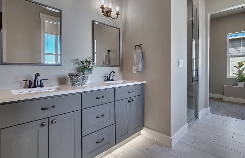 Modern bathroom with grey vanity, antique look fixtures and grey tile flooring