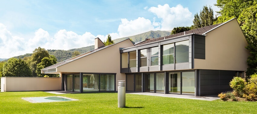 Modern villa exterior with garden brown roof glass doors and windows with view of a mountain