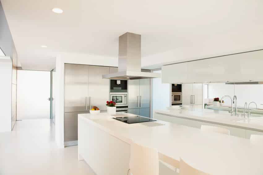 Modern white kitchen with nanoglass countertop center island hood cabinets tile flooring induction stove