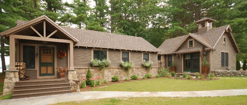 Mountain home with brown brick exterior stone wall trim post and beam in front porch and a concrete walkway