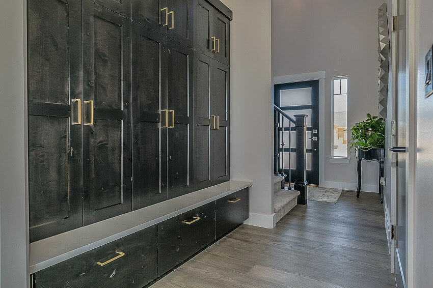 Mudroom with view into the front lobby area stairs black cabinets and wooden floor