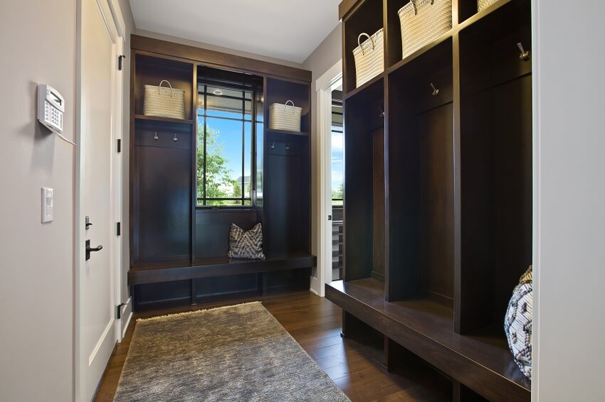 Mudroom with window rug brown wood mud bench and baskets in cubbies