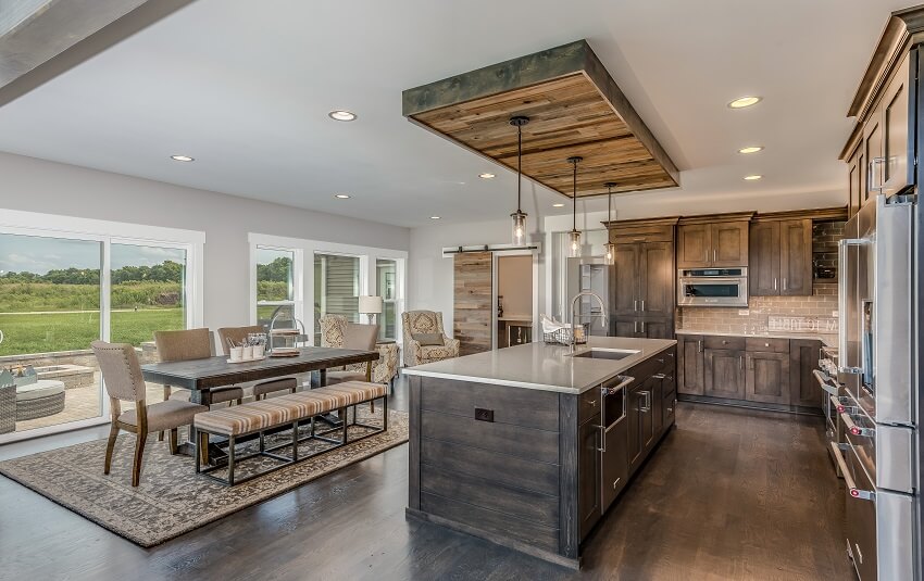 Open kitchen with wood ceiling above island along with wood flooring and cabinets pendant lights dining area and glass doors