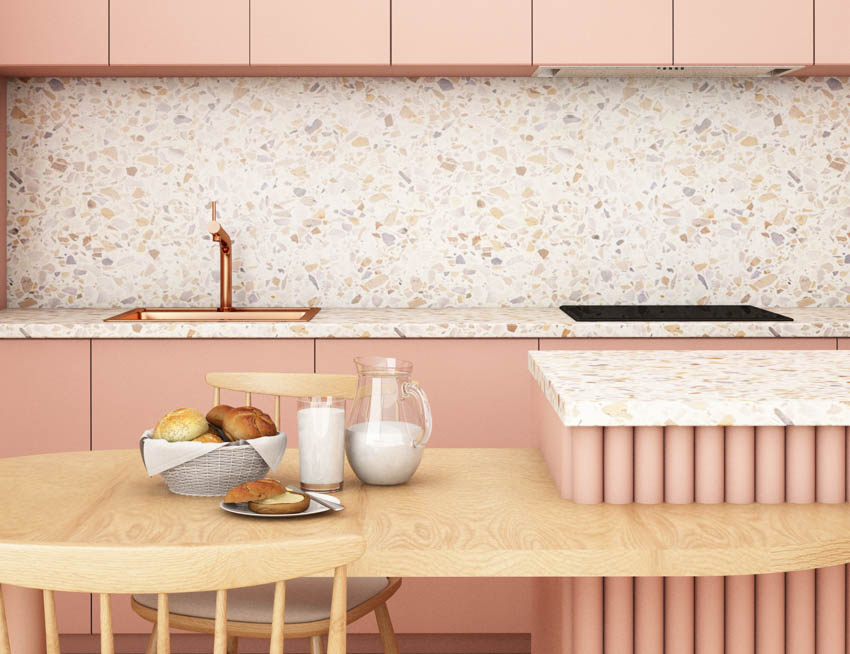 Pink kitchen with recycled glass countertop, backsplash, cabinet, copper sink, faucet, dining table, chair, and center island