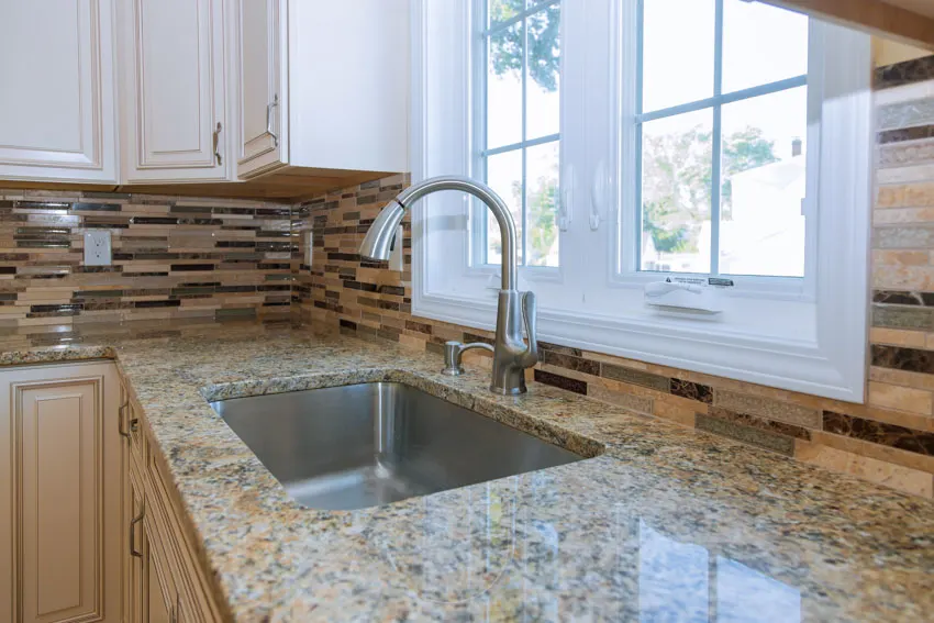 Oyster shell countertop tile backsplash windows white kitchen cabinets sink faucet