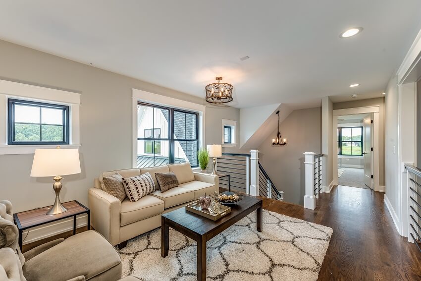 Second floor of a home with cream colored sofa wood coffee table lighting fixtures carpet grey wall and dark wood floors