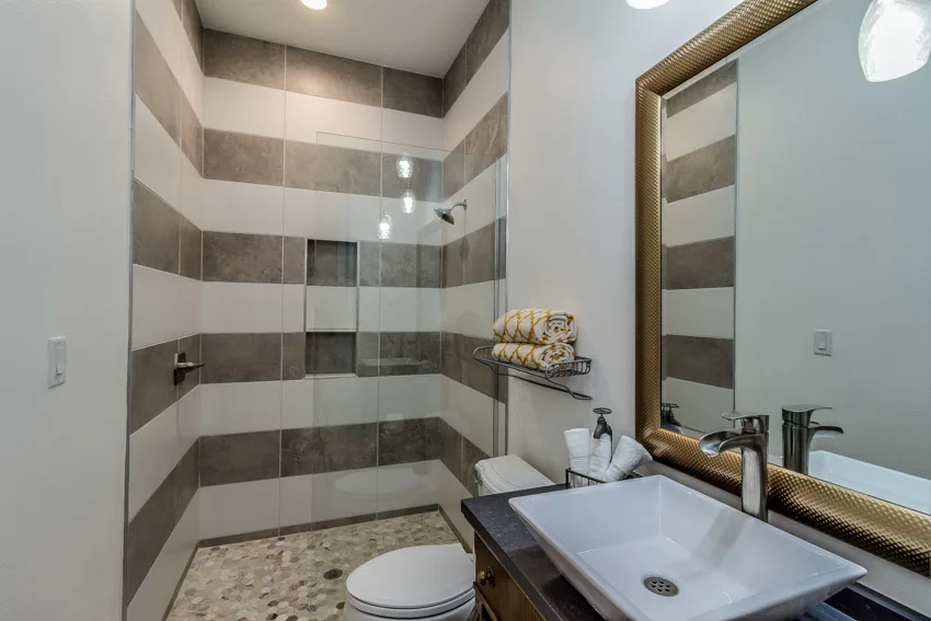 Small bathroom with open shower concept mirror toilet white and brown stripe wall sink