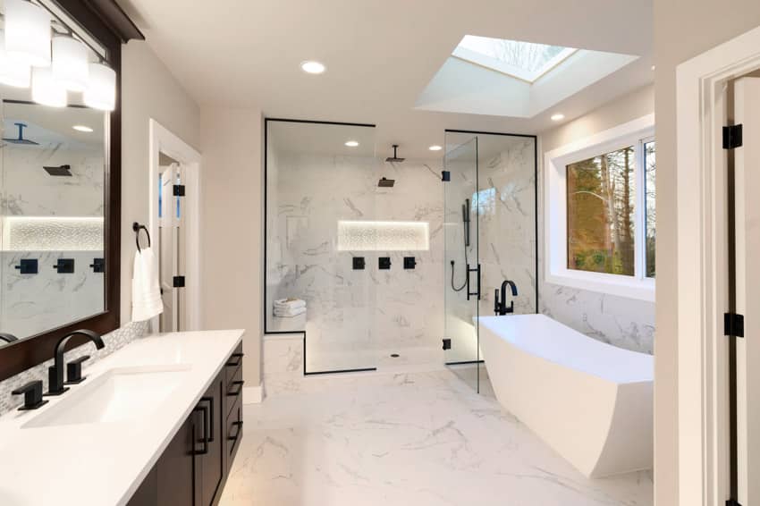 Spacious bathroom skylight tub mirror shower area glass divider sink countertop marble wall