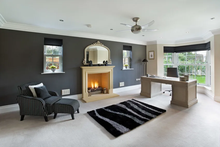 Spacious home office fireplace ceiling fan light black wall rug window recessed lighting chair