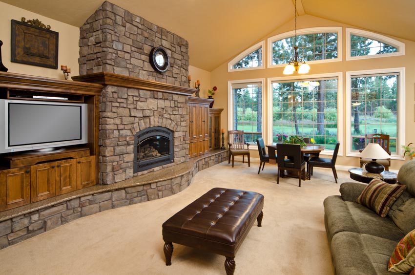 Spacious living room brick fireplace mantel couch dining table chairs windows hanging light wood cabinets 