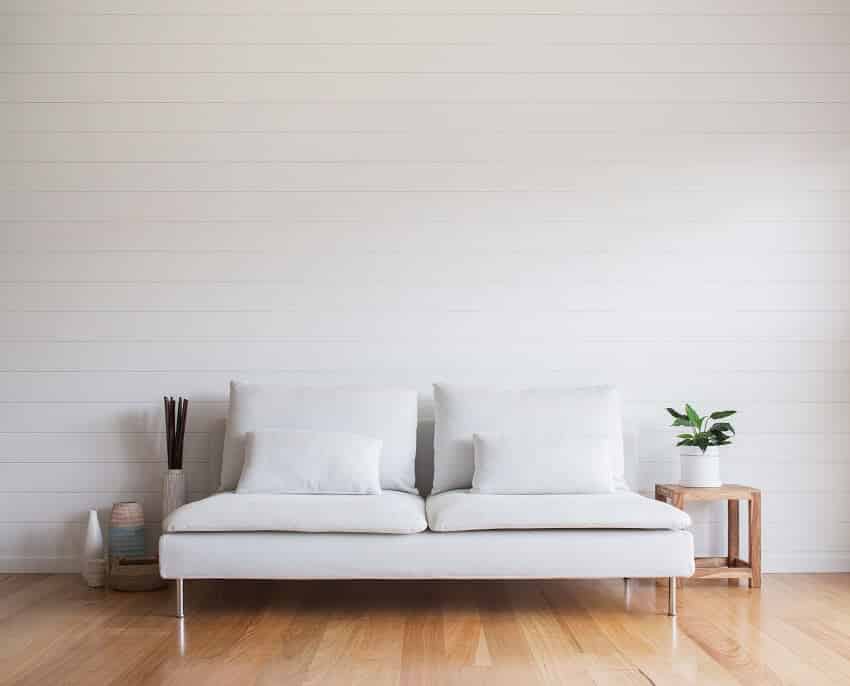 Stylish minimalist living room with white vj paneling walls white couch and timber floor