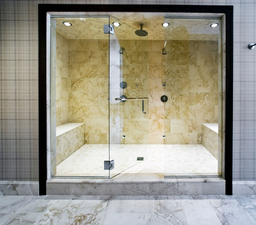 Tiled shower room with a bench lighting fixtures and double showerhead enclosed in a glass