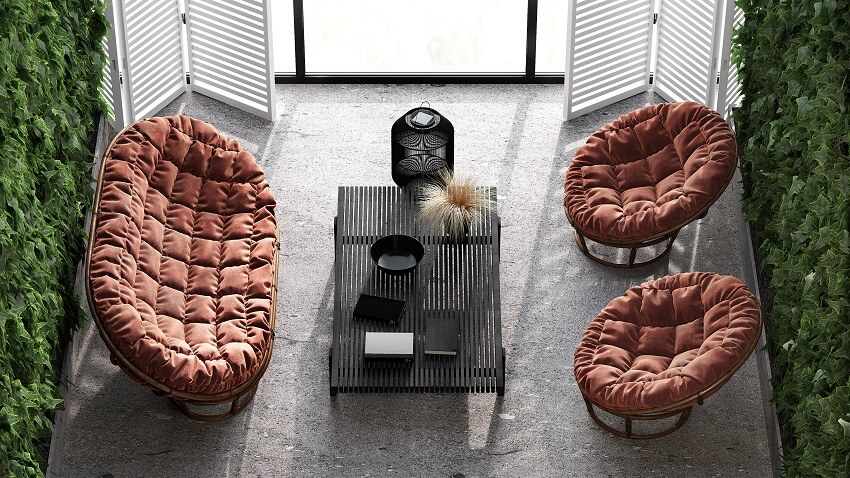 Top view of an indoor terrace with concrete floors green plants on the wall coffee table and a single and double papasan chair