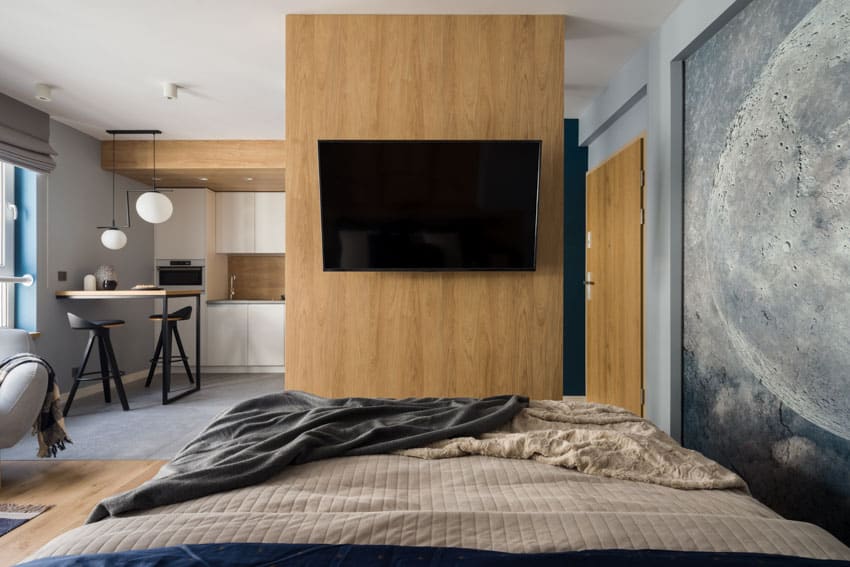 TV mounted above bed wood panel wall windows