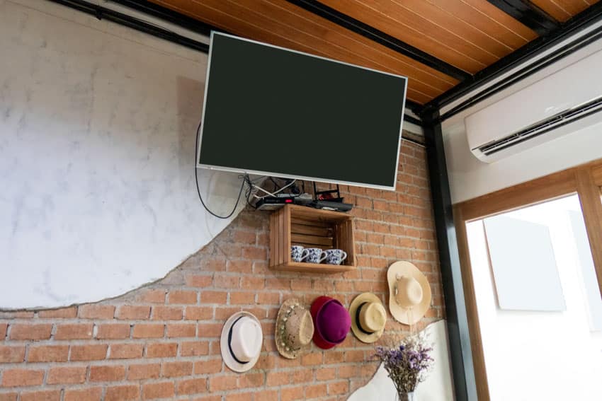 TV mounted near ceiling wood brick wall air conditioner