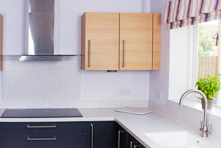 White countertop, wood cabinetry, induction stove hood 