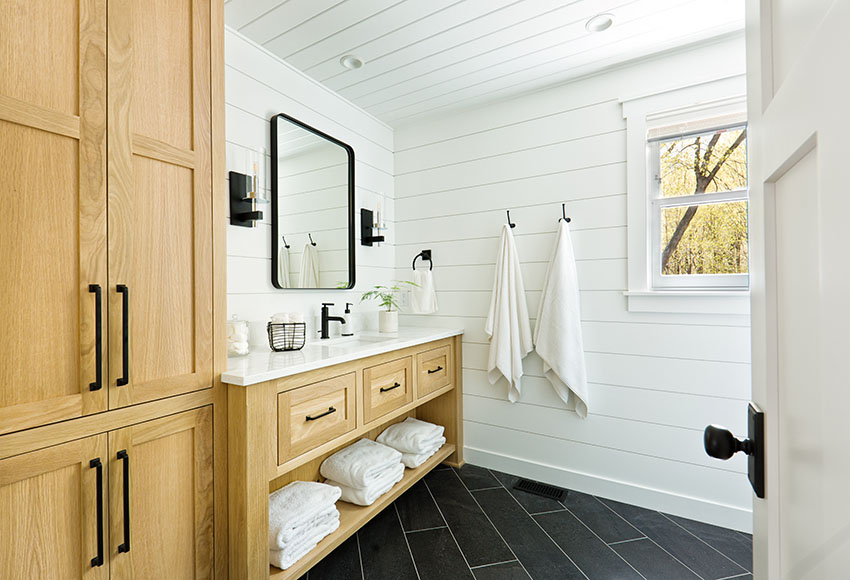 Bathroom powder room with black tile flooring, large vanity and white shiplap wall