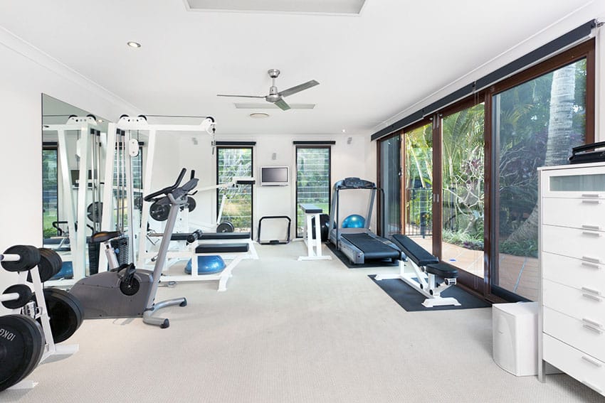 Home gym with sliding barn doors ceiling fan white paint