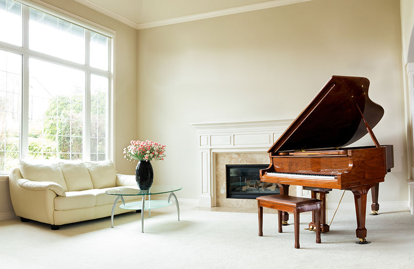 Living room with grand piano, sofa, glass coffee table and insert fireplace