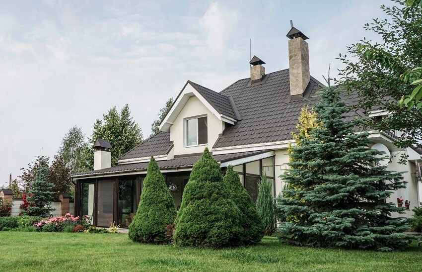 A house with chimneys brown roof lightning rod and a large garden