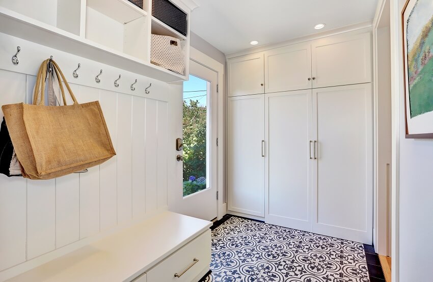 Mudroom with white walls, cabinet, bench and vintage style floral patterned floor