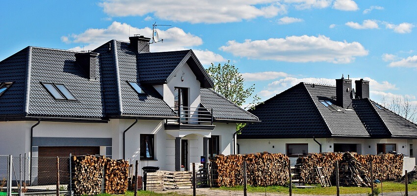 A white luxury house with black roof lightning rod dish antenna skylight windows balcony and stacks of firewood