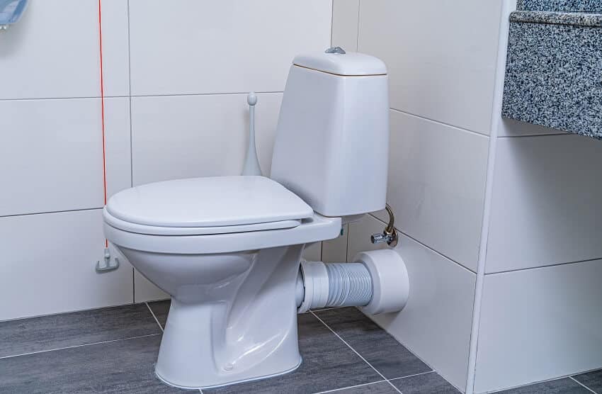 A toilet, tile floor and terrazzo countertops in a bathroom