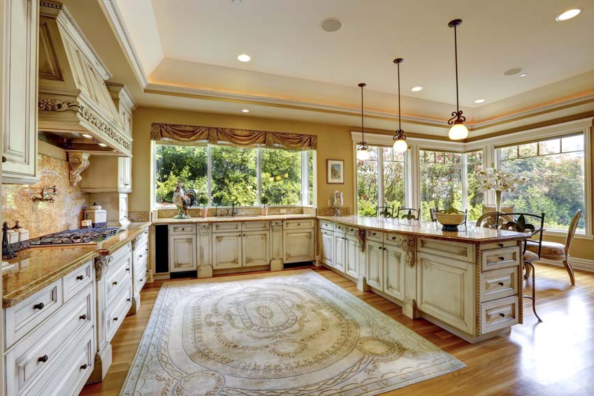 Antique white kitchen with cabinets, pendant lights, floor rug, wood flooring, windows, and countertop