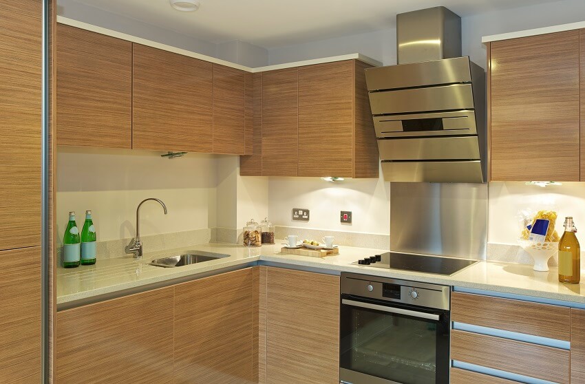 Apartment kitchen with bamboo cabinets granite countertops integral oven hob extractor fan unit and under cabinet lighting