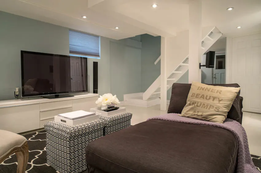 Basement bedroom with light green walls, television, and ceiling lights