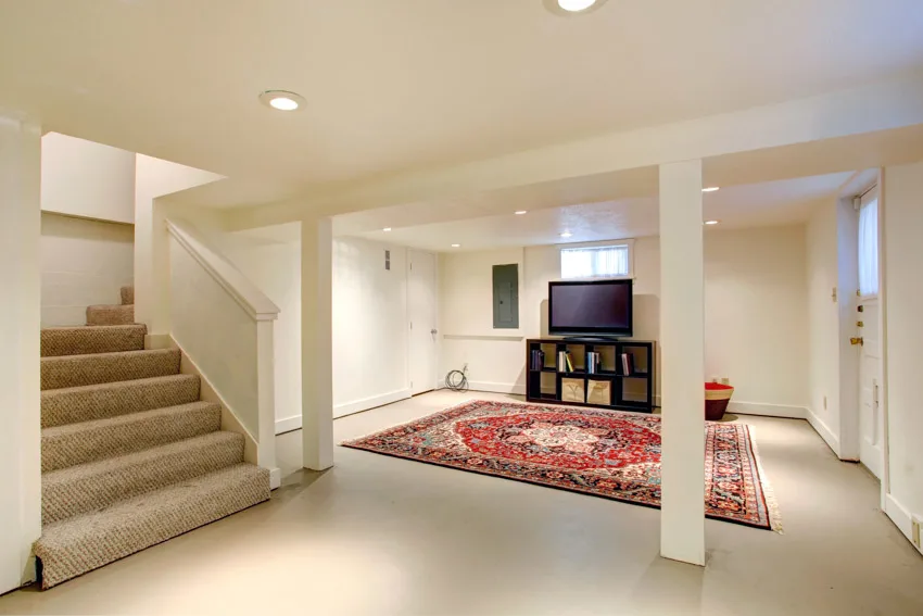 Basement painted floor staircase, rug, television, and recessed lights