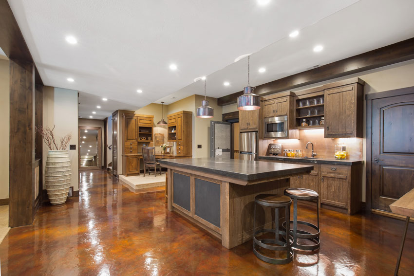 Basement kitchen with painted concrete floor, center island, wood cabinets, recessed lighting, and stools
