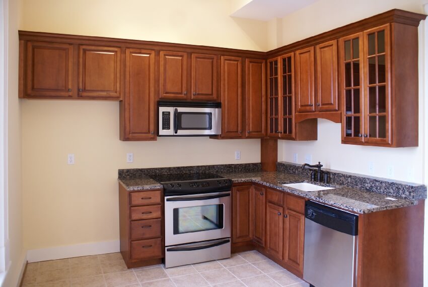 Basic kitchen with cream wall paint granite countertop appliances and cherry cabinets