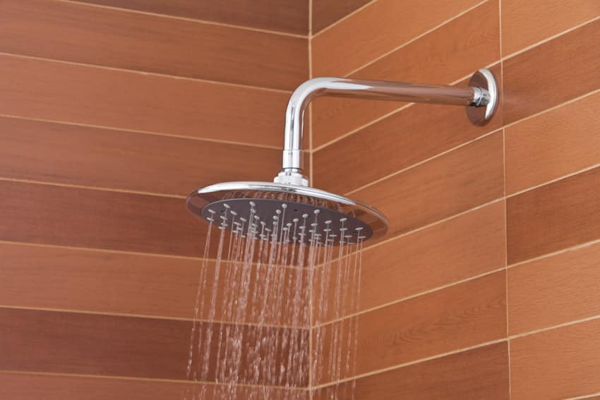 Bathroom shower head installed on red tile wall